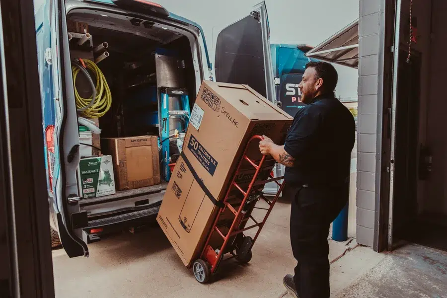 Technician loading new equipment in Stellar Plumbing van.